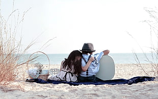 boy and girl sitting in front of the ocean wearing white and teal outfits holding guitar