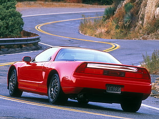 red coupe on gray asphalt road at daytime