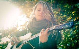 woman in black long-sleeved shirt playing acoustic guitar