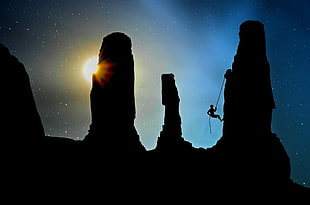 silhouette of person climbing cliff during nighttime HD wallpaper
