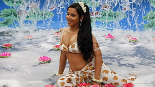 woman in white and yellow bra and pants sitting near body of water
