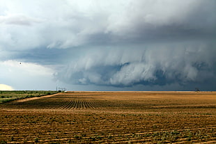 brown field under gray clouds during  daytime