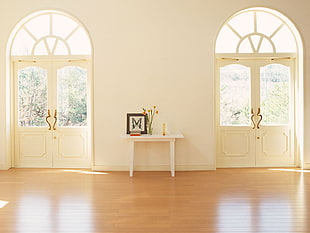 white console table in the middle of white painted wall in between two 2-door windows