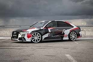 red, black, and white Audi A-Series sedan on gray top road