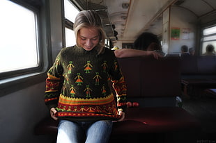 woman wearing green and yellow crew-neck sweater sitting inside brown vehicle seat