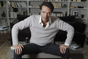 photo of man wearing gray sweater sitting on coffee table