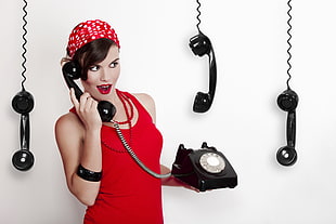 woman in red tank top answering black telephone