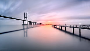 silhouette of bridge over calm body of water HD wallpaper