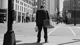 grayscale photo of man holding mask and duffel bag