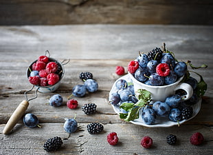 blueberries, raspberries, and blackberries in ceramic teacup with saucer