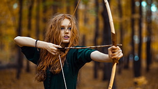 redhead woman drawing arrow from bow