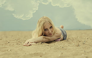blonde haired woman lying on brown sand
