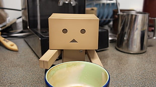 blue mug and brown cardboard robot on table