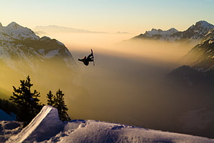 silhouette photo of person plays snowboard during golden hour