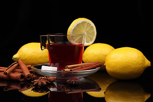 four yellow lemons beside clear glass mug with tea
