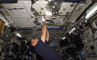 male astronaut fixing something at the top deck