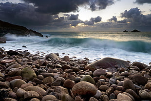 seashore stones near body of water during daytime