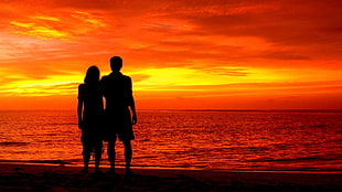 silhouette of a man and woman near shoreline HD wallpaper