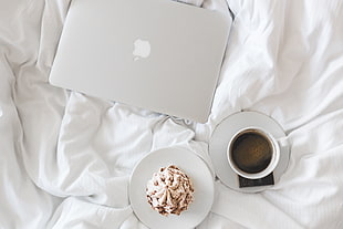 white Macbook, coffee and cupcake on bed