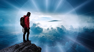 man wearing red jacket on top of hill