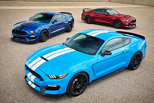 three assorted-color Ford Mustangs