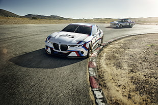 white BMW racing car running on curve road during daytime