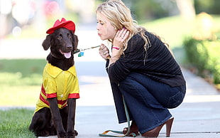 woman wearing black sweater and blue jeans holding black dog during daytime