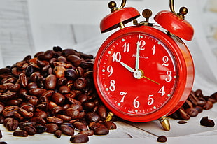 red alarm clock at 10:00 beside brown coffee beans