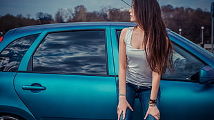 woman leaning on blue 5-door hatchback