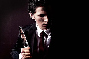 man wearing black formal wear while holding knife