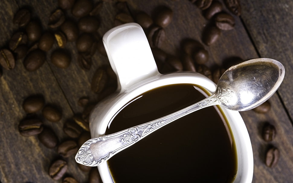stainless steel spoon on top of white ceramic mug surrounded with coffee beans HD wallpaper