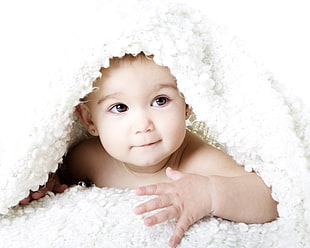 shallow focus photography of toddler covered by white blanket