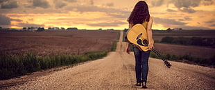 woman standing carrying acoustic guitar
