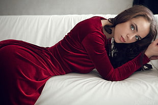 woman wearing red suede long-sleeved dress while lying on white bed comforter HD wallpaper