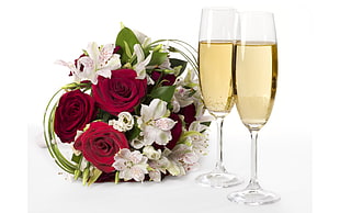 two clear glass champagne flutes and rose bouquet