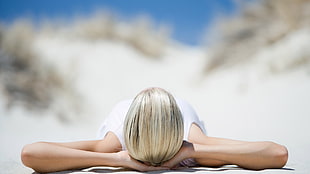 woman sun bathing on white sand beach
