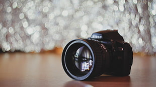 bokeh photography of Nikon DSLR camera on brown surface