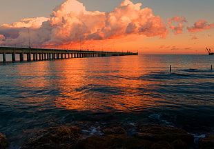 full-suspension bridge on top of body of water during orange sunset HD wallpaper