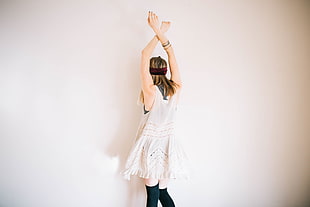 woman wearing white sleeveless top raising her hands