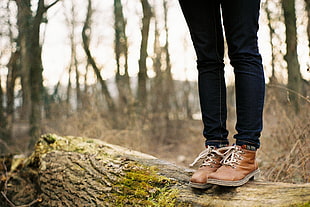 person wearing pair of brown leather boots standing on brown fire wood during day time