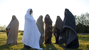 six person covered in blankets in green grass field