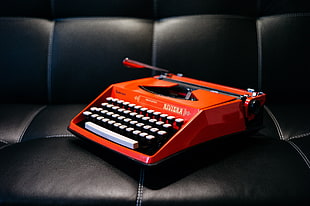 orange and white typewriter on black leather sofa HD wallpaper