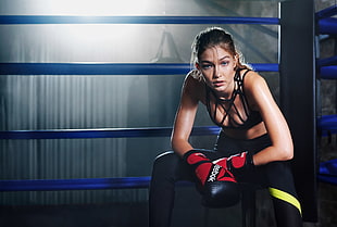 woman wearing black sports bra and pair of black-and-red Reebok boxing gloves