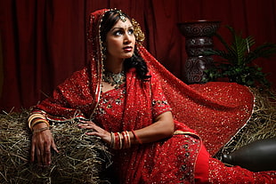 woman wearing red traditional dress sitting on hay