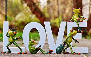 four red eyed frog figurines near white love cutout free standing letters HD wallpaper