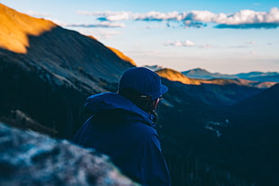 man wearing blue cap and hoodie sitting