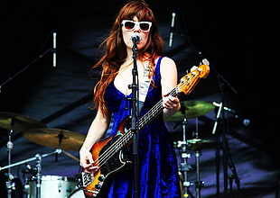 woman holding bass guitar wearing blue sleeveless dress