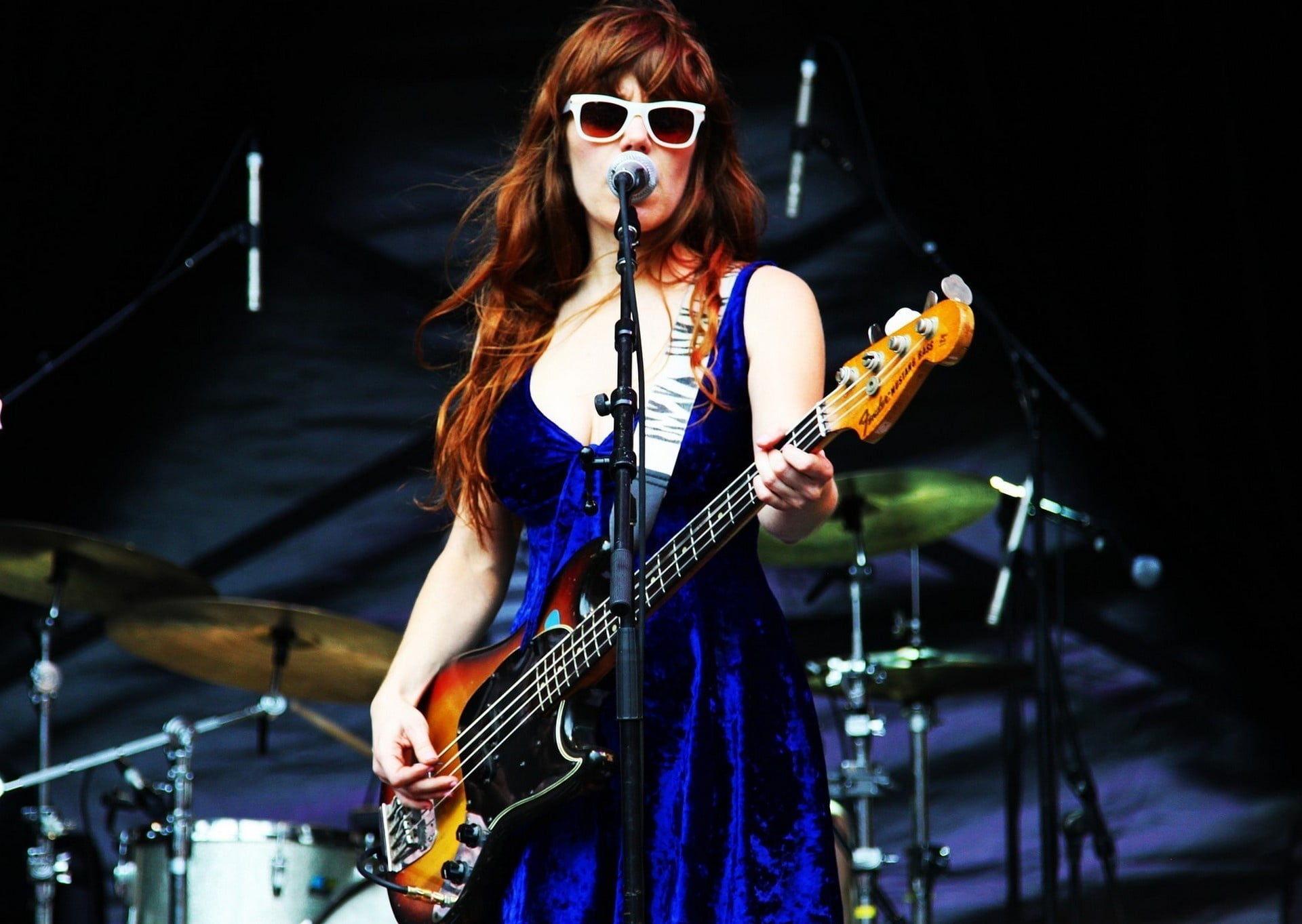 woman holding bass guitar wearing blue sleeveless dress
