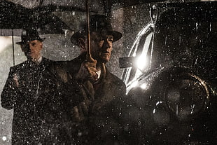 man in black coat under umbrella beside vehicle HD wallpaper