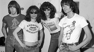 grayscale photo of four men wearing crop top shirts and highwaisted pants